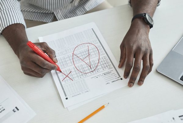 A man sat at a table grading a piece of work