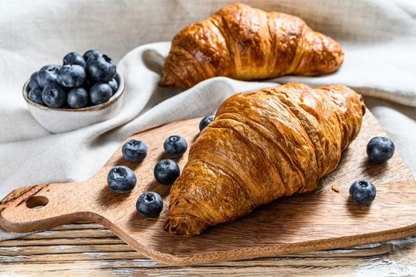 croissants with blueberries on a wooden platter