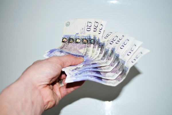 A hand holding multiple pound notes