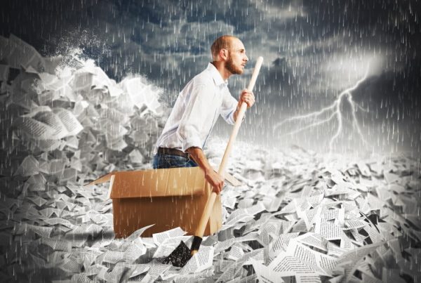 A man in a cardboard box paddling through paper