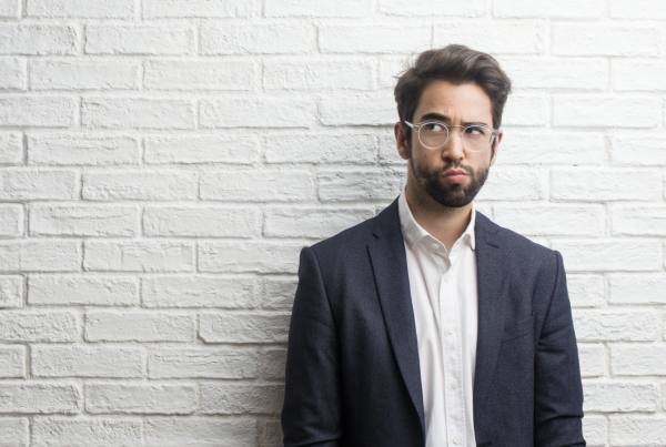 A man stoor Infront of a white wall pondering