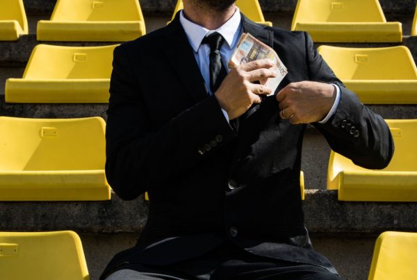 A man in a suit holding money at a sports venue
