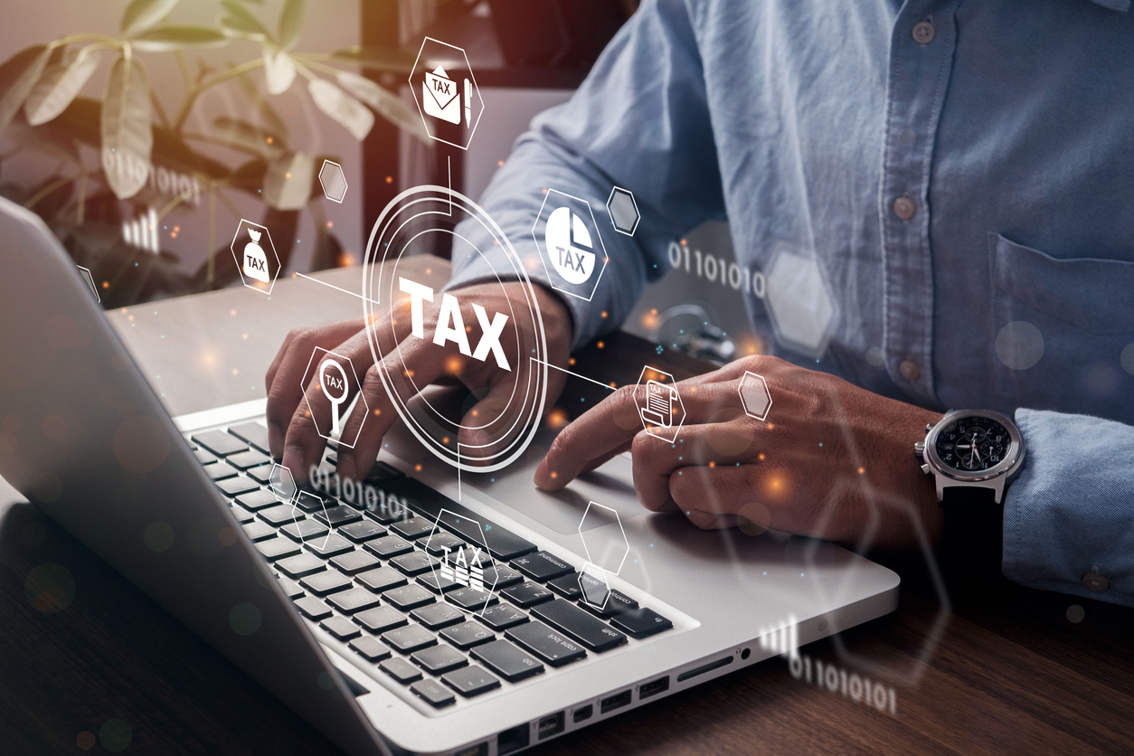 Person using a laptop with digital tax graphics